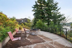 An outdoor patio with stone flooring, a stone fire pit, and red chairs. - Beachfront Condo Retreat at Delton Grand (Wisconsin Dells)