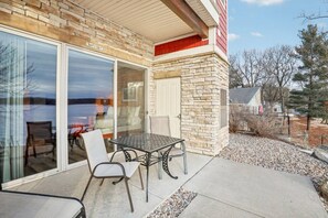 A patio with a table and chairs, a stone wall, and a sliding glass door.
