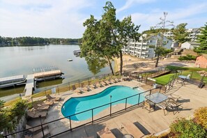 A swimming pool with lounge chairs and a view of a lake and buildings.