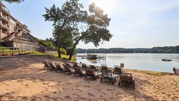 Une plage avec des chaises longues et une vue sur un lac.