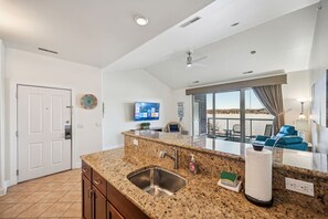 A modern kitchen with granite countertops, a stainless steel sink, and a flat-screen TV mounted on the wall. - Beachview Twin #1 at Delton Grand (428) (Wisconsin Dells)