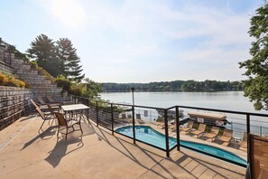 A poolside area with a view of a lake, outdoor furniture, and a stone retaining wall. - Beachview Twin #2 at Delton Grand (429) (Wisconsin Dells)