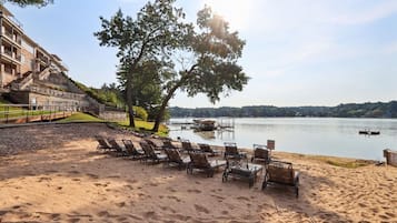 A beach with sun loungers and a view of a lake.