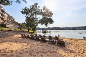 Une plage avec des chaises longues et une vue sur un lac.
