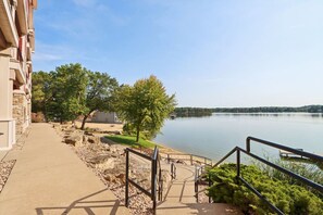 A lakeside walkway with a stone path, a metal railing, and a view of a calm lake. - Beachview Twin #2 at Delton Grand (429) (Wisconsin Dells)
