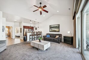 A spacious living room with a modern ceiling fan, a grey sofa, a coffee table, and a dining area in the background. - Beachview Twin #2 at Delton Grand (429) (Wisconsin Dells)