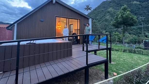 A modern building with a wooden deck and a glass door entrance. - Cocora Valley Cabin (Quindío)