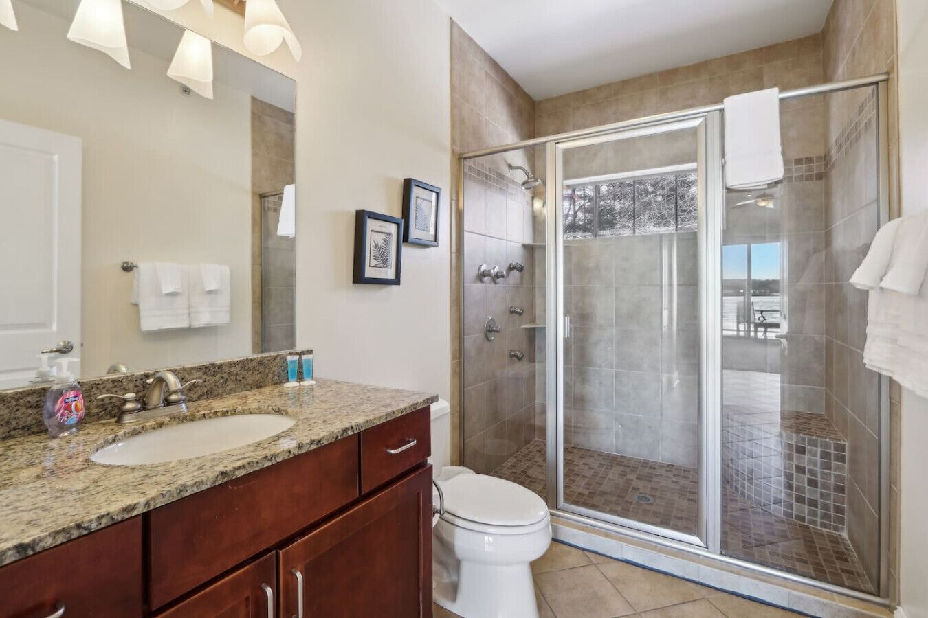 Un baño moderno con lavamanos de granito, inodoro y cabina de ducha con paredes de vidrio.