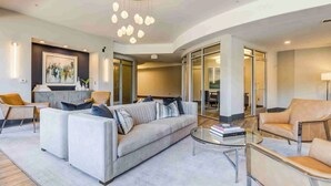 Ein modernes Wohnzimmer mit einer Couch, Sesseln, einem Couchtisch und einem Chandelier.