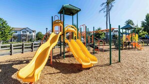 A playground with two yellow slides and a climbing structure.