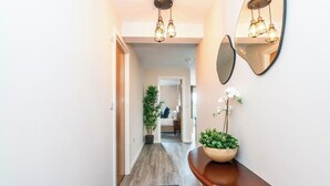 A hallway with a wooden console table, a mirror, and a potted plant. - Modern 2bed Manchester+ parking (Manchester)