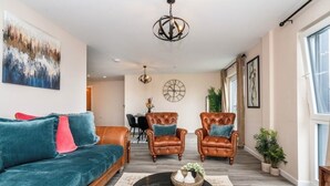 A living room with a sofa, two leather armchairs, a coffee table, and a chandelier. - Modern 2bed Manchester+ parking (Manchester)