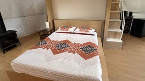 A bunk bed with a wooden frame, a white mattress, and a patterned blanket. There is a ladder on the right side and a small table with a lamp on the left. - Lake view lovers nest (Denison)