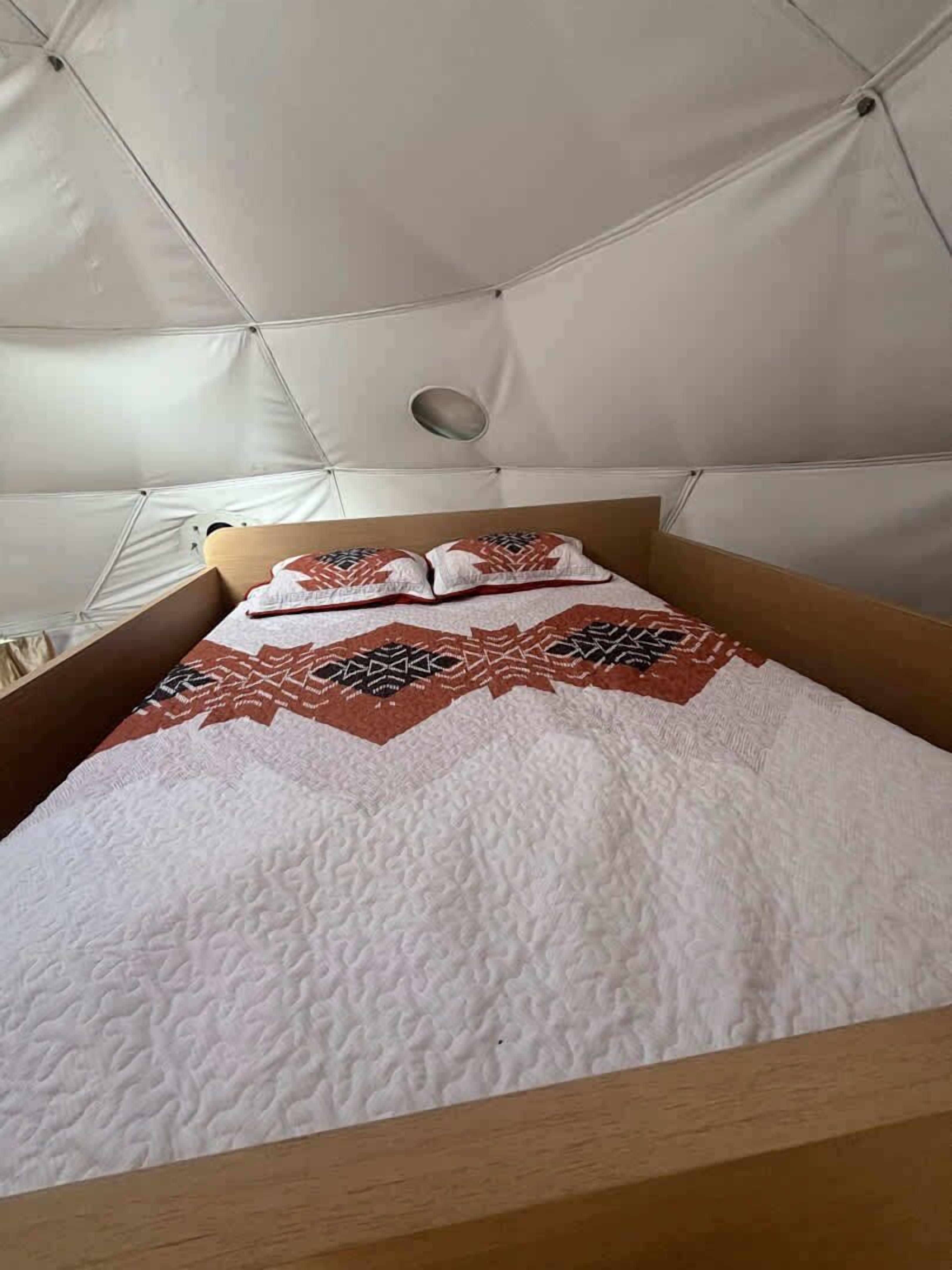 A tent-style room with a bed, pillows, and a quilt.