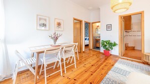 Une pièce spacieuse avec une table et des chaises en bois, un luminaire suspendu et une plante en pot.