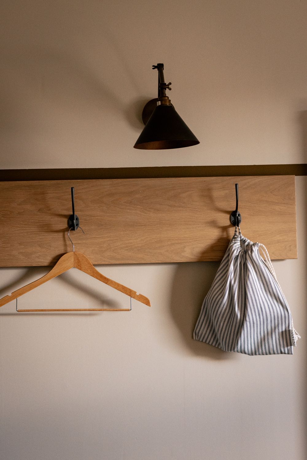 Pared de madera con un perchero de madera y un bolso a rayas.