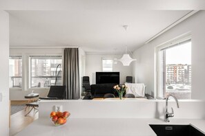 Cozinha moderna com uma janela grande, área de jantar com sofá e mesa, e sala de estar com TV e assentos.