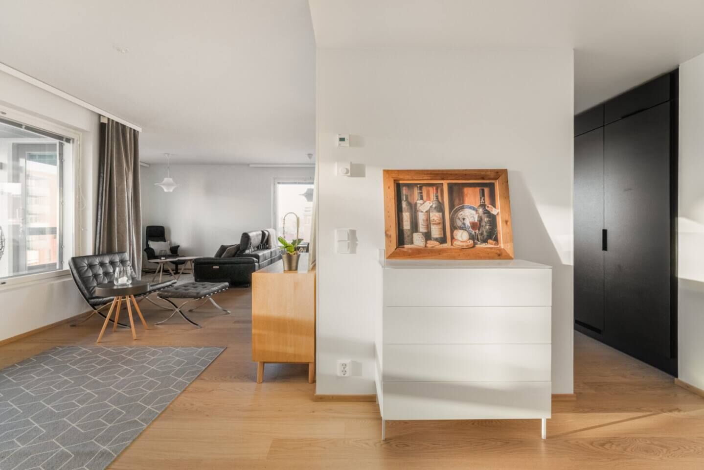 A modern living room with a dining area, a wooden cabinet, and a painting on the wall.