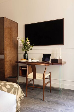 A hotel room with a wooden desk, a laptop, a vase with flowers, a bed with a patterned blanket, and a large black screen on the wall. - Bourgogne Hostel - Room 22- 2P - Invalides (Paris)