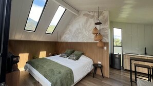Un dormitorio moderno con una cama grande, ventanas de tragaluces, una zona de cocina y una mesa de comedor.