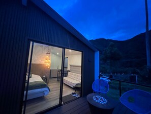 A modern hotel room with a large sliding glass door leading to a balcony. The room includes a bed, a small table, and a chair. - Bosques de Cocora Donde Juan B (Salento)