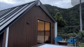 Um edifício moderno com telhado inclinado e uma grande banheira de hidromassagem num terraço.