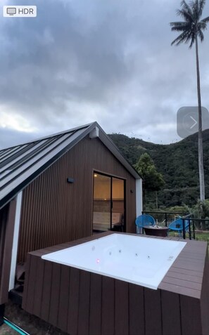 Ein modernes Gebäude mit einer geneigten Dachfläche und einer großen Whirlwanne auf einer Terrasse.