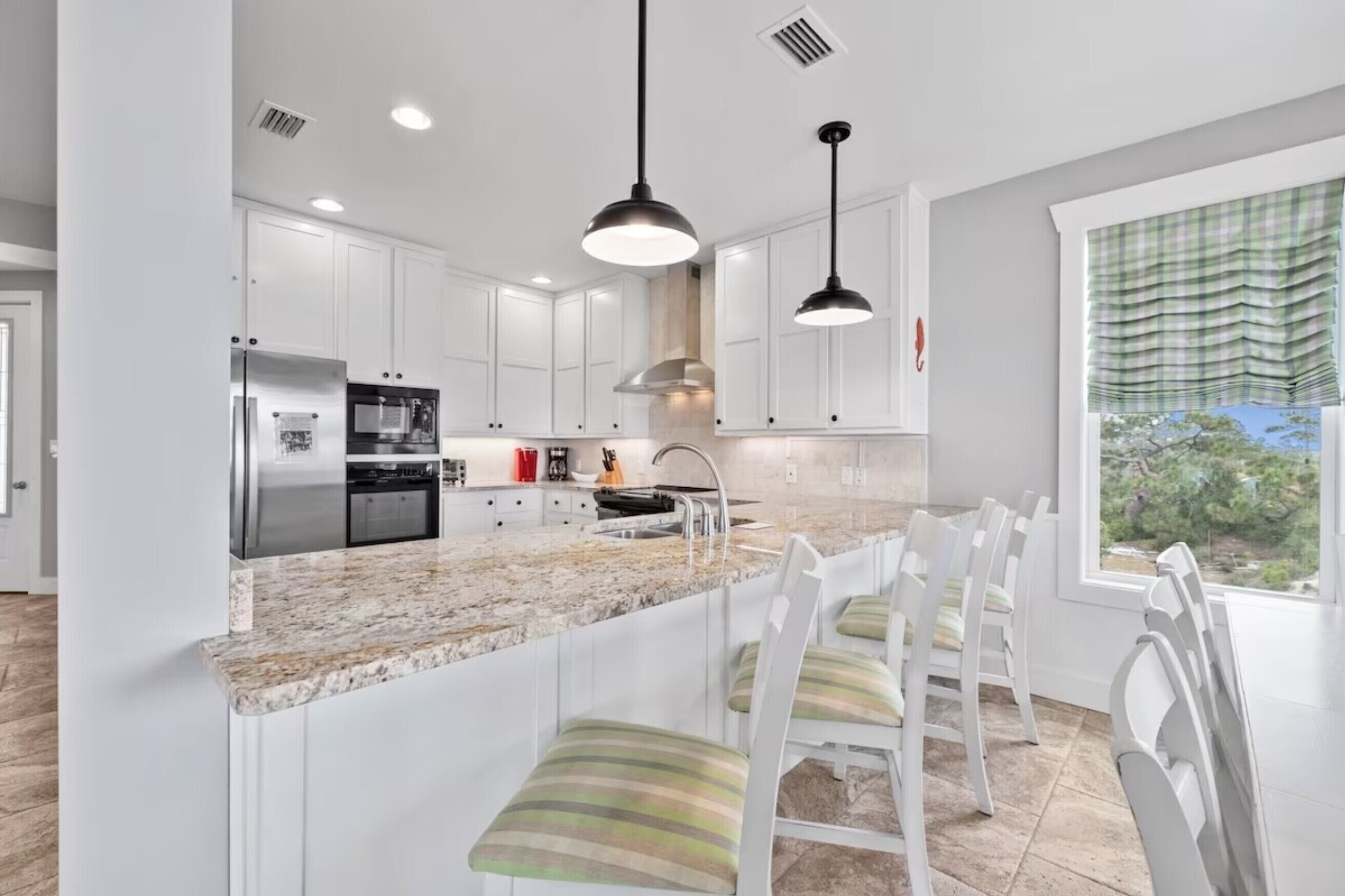 A modern kitchen with white cabinets, a granite countertop, and pendant lighting.