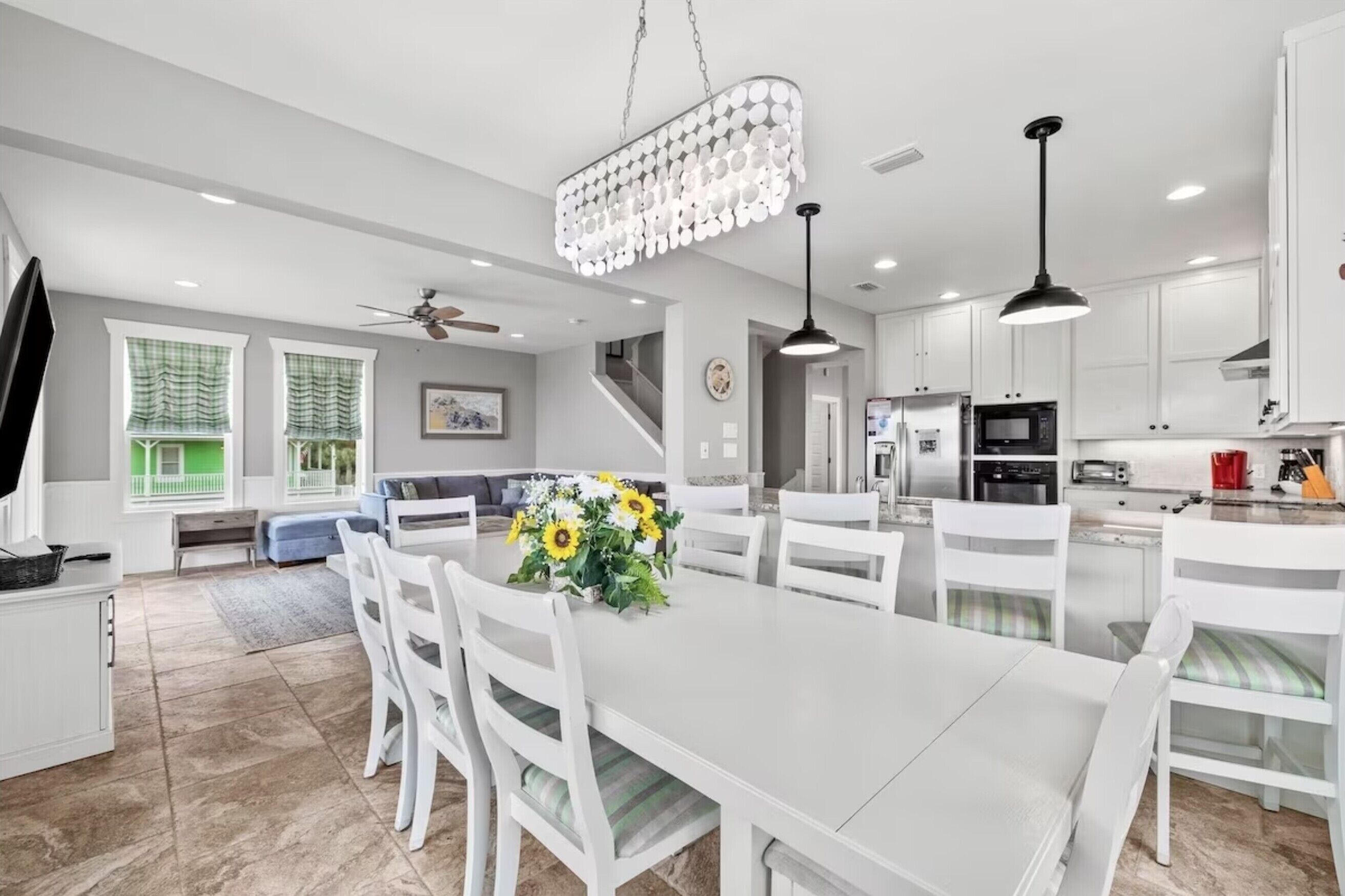 Une cuisine moderne avec des meubles blancs, une table à manger avec des chaises et un lustre.