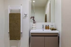 A bathroom with a white sink, a mirror, and a towel rack with a brown towel. - Acropolis Penthouse Plunge Pool (Athina)