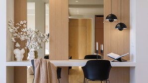 A modern dining area with a white table, black chairs, and a vase of white flowers. - Acropolis Penthouse Plunge Pool (Athina)