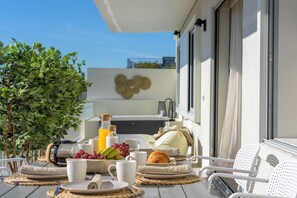 Een ontbijtje buiten, compleet met een tafel, stoelen en allerlei lekkernijen zoals fruit, gebak en drankjes.