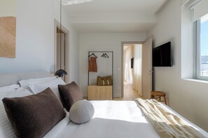 Een moderne hotelkamer met een opgemaakt bed, een flatscreen televisie aan de muur en uitzicht op de stad.