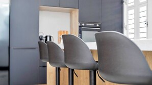 Una cocina moderna con armarios oscuros, encimera de madera y horno empotrado.