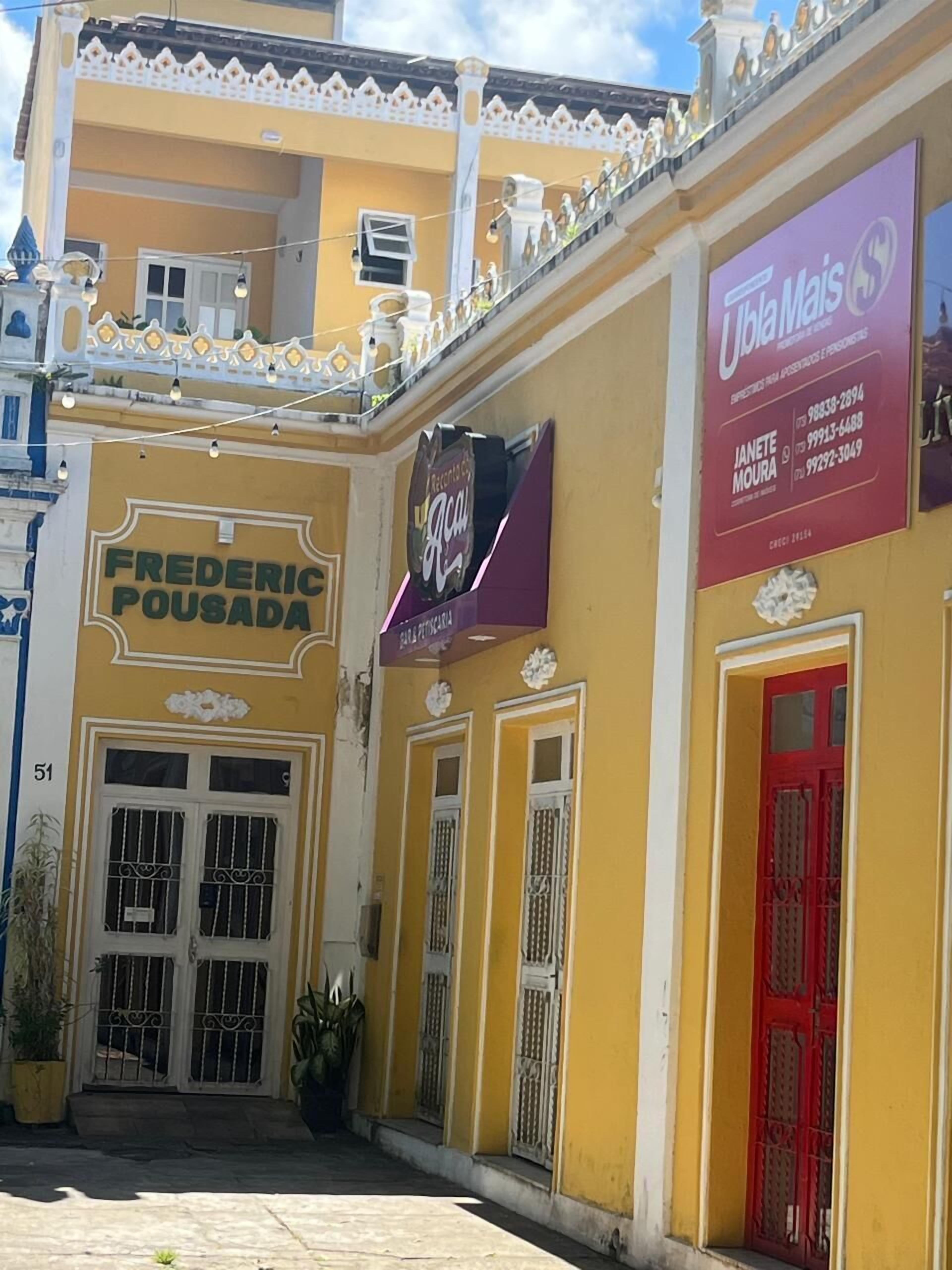 A yellow building with a sign for Frederic Pousada and a business sign for Janete Moura.