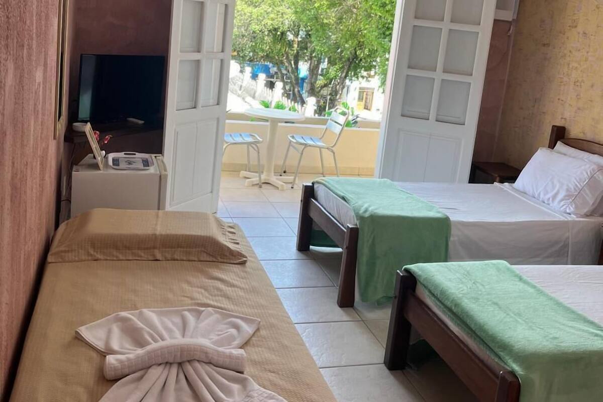 A hotel room with two beds, a TV, a desk, and a view of the outside.