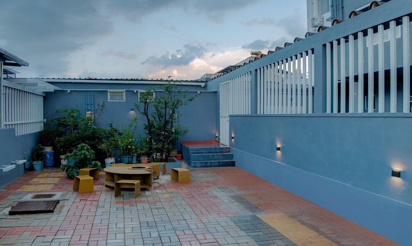 Une cour avec un mur bleu, des sièges en plein air et des plantes en pot.