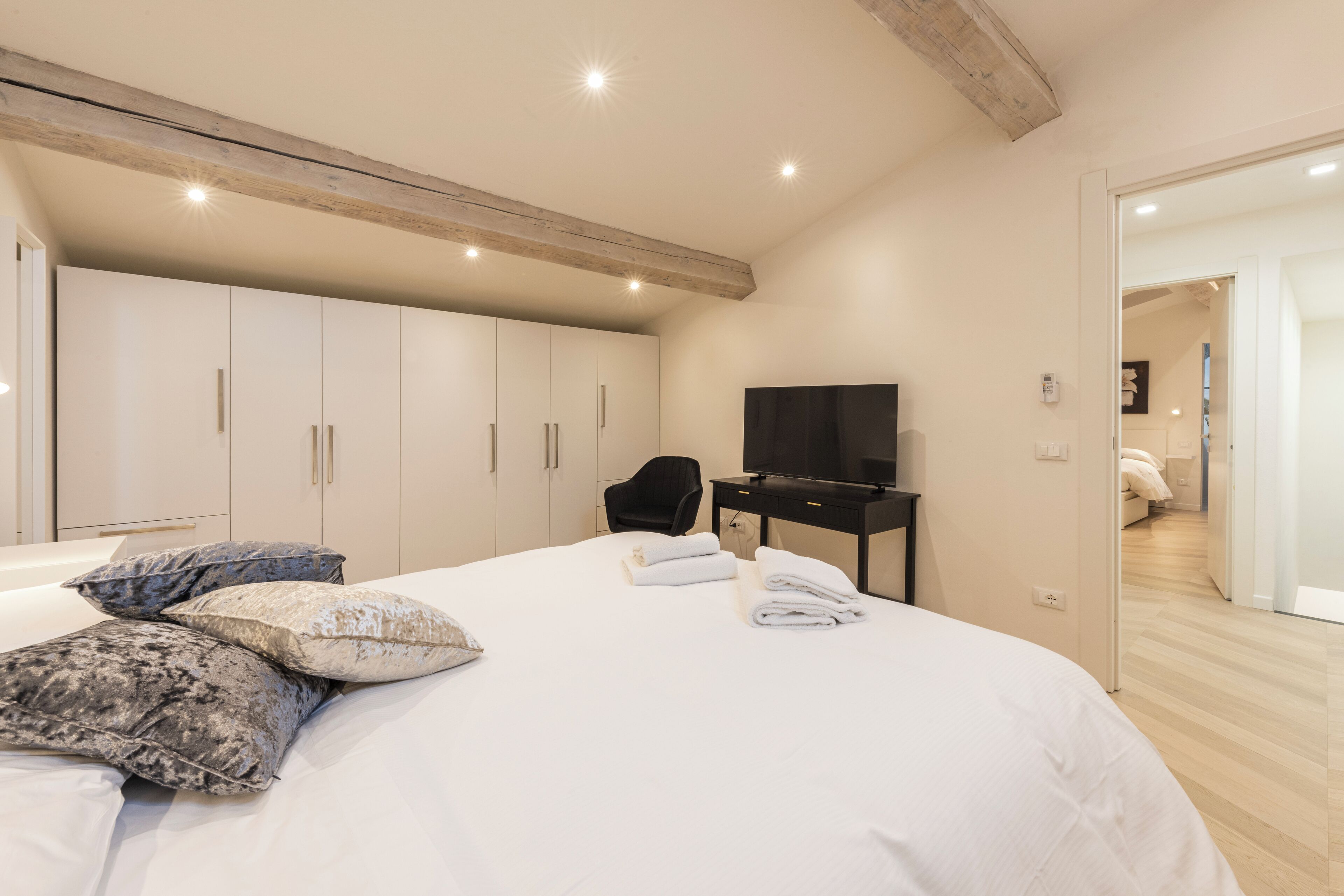 A bedroom with a large bed, a TV, and a wardrobe.