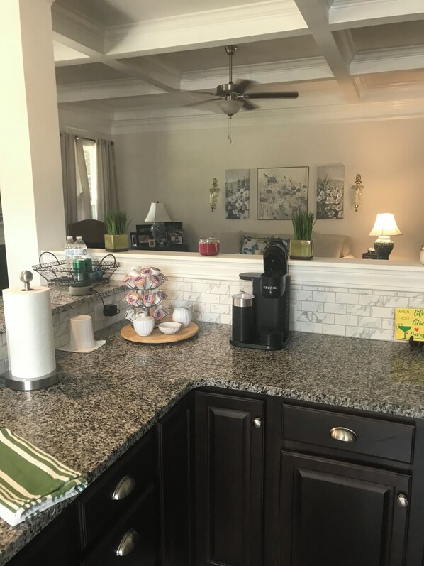 A kitchen with granite countertops, a coffee maker, a kettle, and a microwave. There are cabinets and a ceiling fan. - Masters Golf Tournament rental on Mt. Vintage Golf Course, New, Beautiful Home (North Augusta)