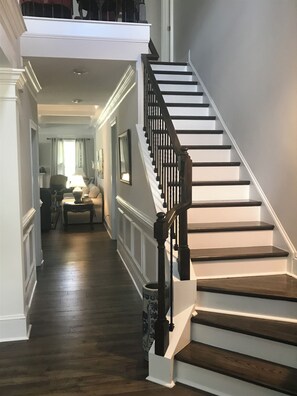 A grand staircase with dark wooden steps and white walls, leading to an upper landing. - Masters Golf Tournament rental on Mt. Vintage Golf Course, New, Beautiful Home (North Augusta)