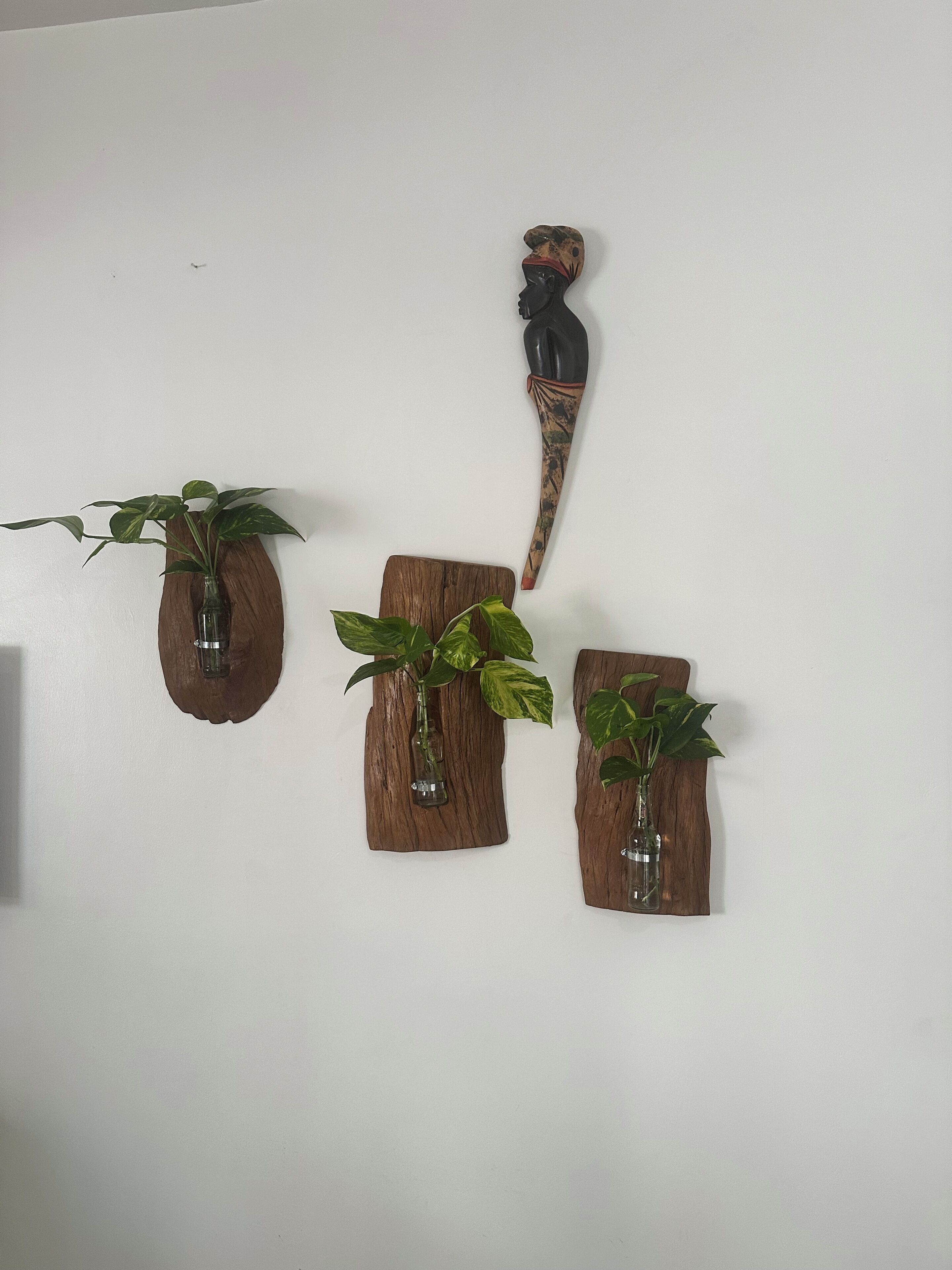 Three wooden planters with plants on a white wall.