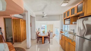 Una cocina amplia con gabinetes de madera, un refrigerador de acero inoxidable y un comedor con una mesa redonda y sillas.