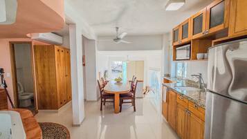 A spacious kitchen with wooden cabinets, a stainless steel refrigerator, and a dining area with a round table and chairs.