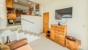 Una sala de estar moderna con una escalera, muebles de madera, un televisor de pantalla plana y una zona de comedor.