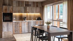 Una cocina rústica con paredes de madera, horno empotrado, pileta y zona de comedor con mesa y sillas.