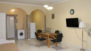 Um espaço compacto com área de refeições, máquina de lavar, televisão e luminária.