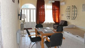 Um espaço compacto com mesa de jantar, duas cadeiras, sofá e cama.