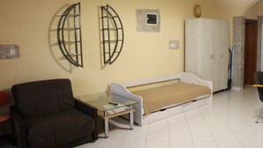 Um quarto com sofá, uma mesinha, cama e guarda-roupa.