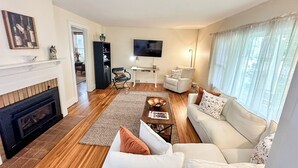 Una sala de estar con chimenea, sofá, mesa de centro y televisor.