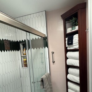 Large walk in shower  with grab bar.  Towel tower for ease and accessibility.